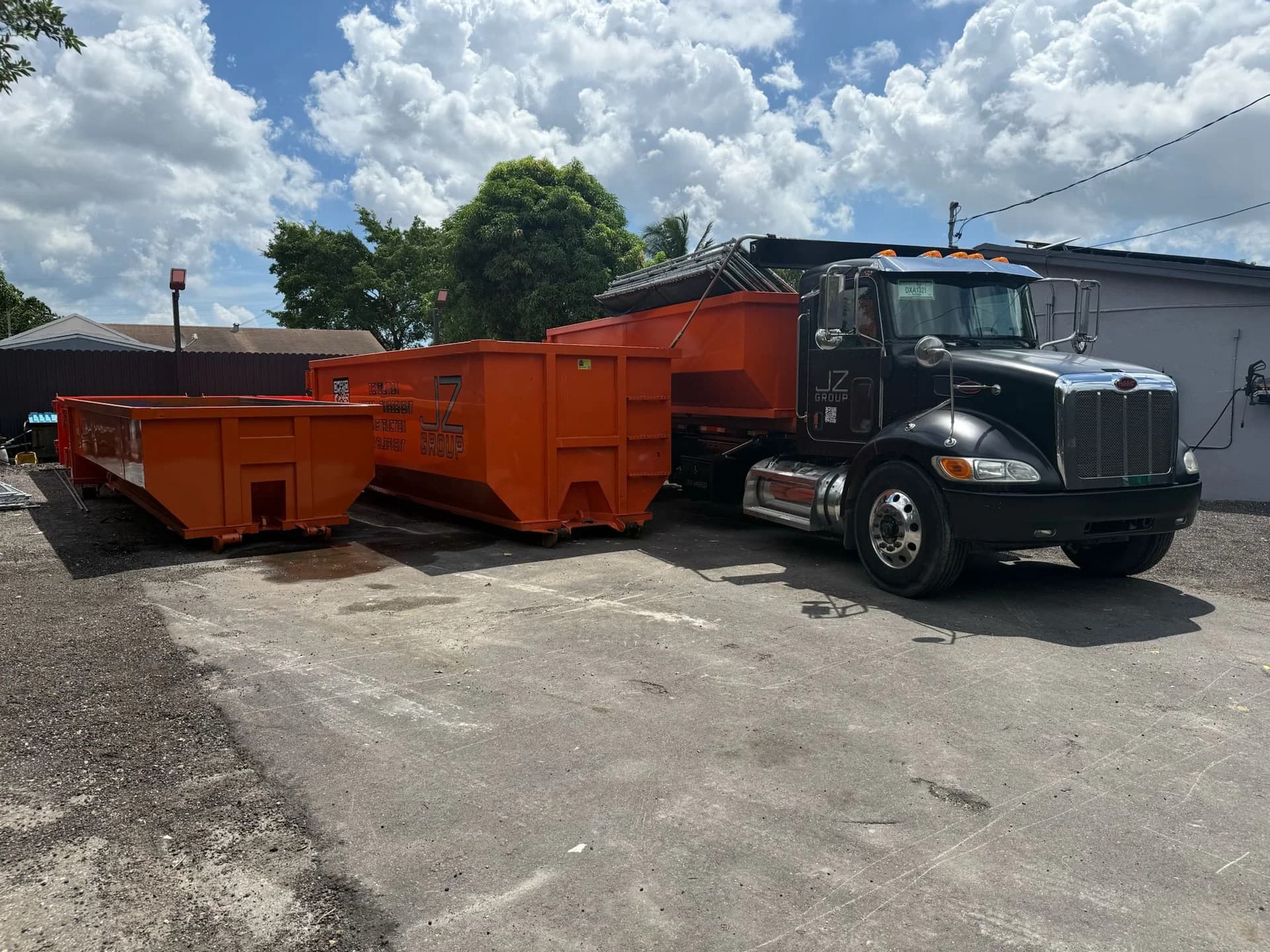 Orange roll-off containers and a black truck in a paved yard