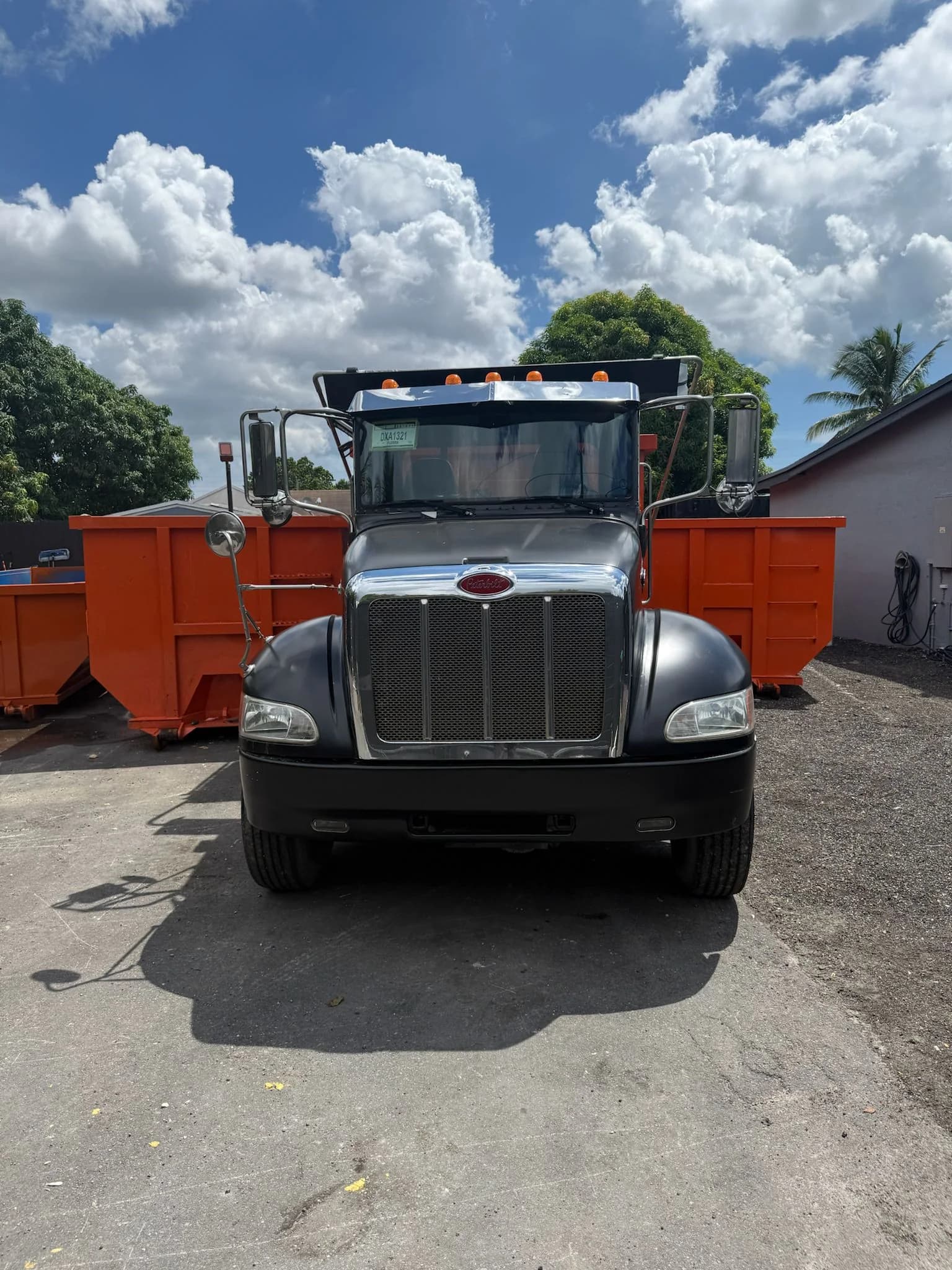 JZ hauling truck parked among orange roll-off containers in the yard