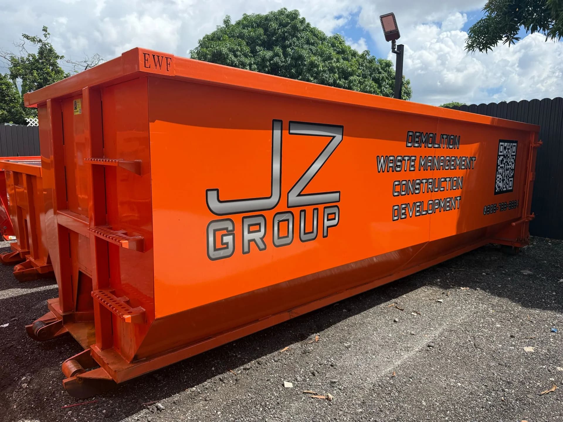 An orange JZ Group roll-off container in the yard